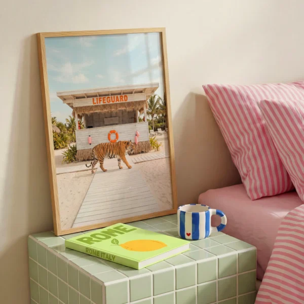 Framed tiger lifeguard stand wall art styled beside pink striped pillows in a Palm Springs-inspired bedroom