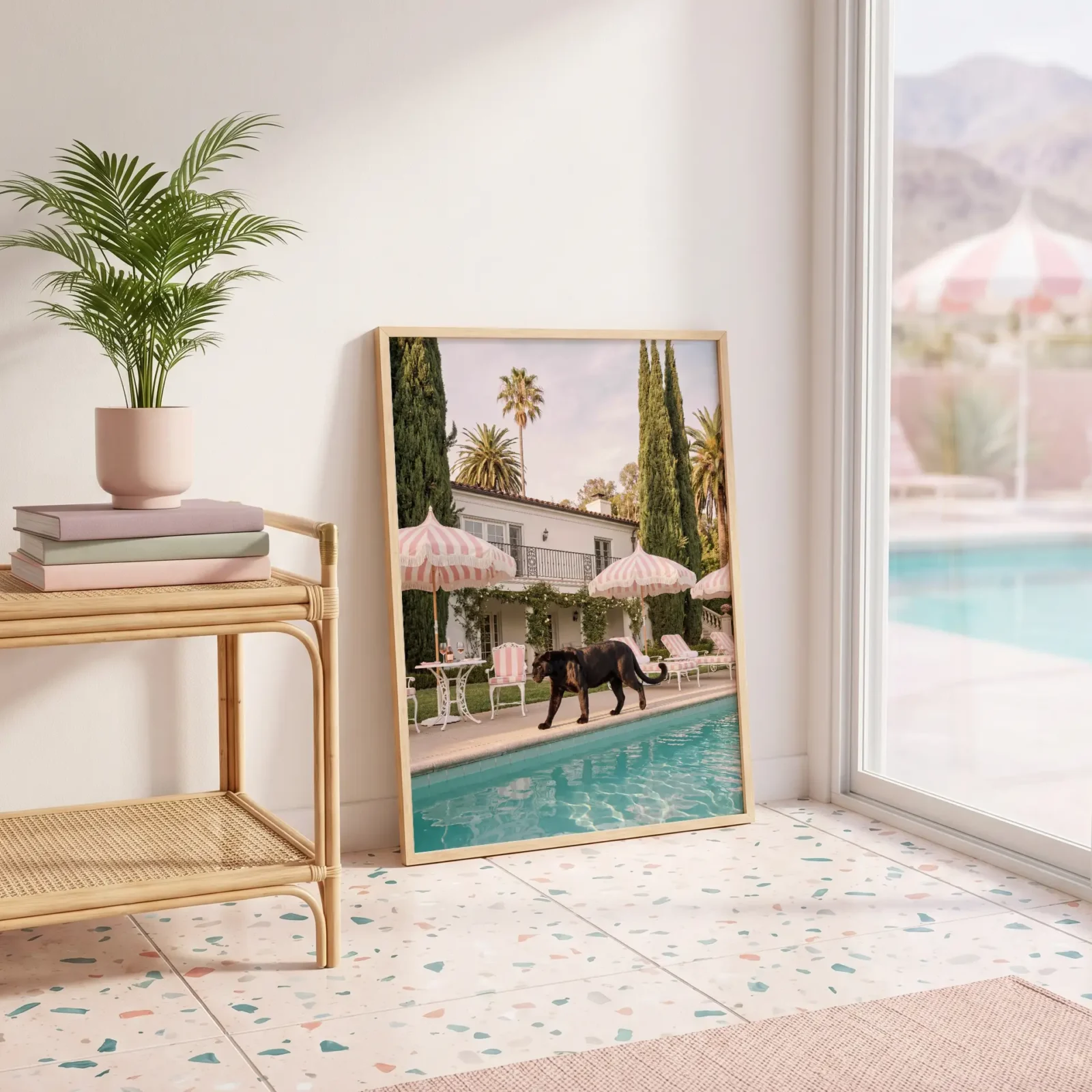 Framed black panther poolside wall art leaning beside a rattan console in a bright resort-style interior